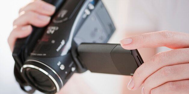 Woman using digital camcorder, close-up