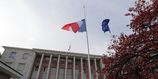 French national flags and an European Union flag are lowered at half staff over the French embassy as embassy personnel and members of French community observe a minute of silence in Ankara, Turkey, Monday, Nov. 16, 2015. French police raided more than 150 locations overnight as authorities released the names of two more potential suicide bombers involved in the Paris attacks, one born in Syria, the other a Frenchman wanted as part of a terrorism investigation.(AP Photo/Burhan Ozbilici)