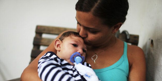 RECIFE, BRAZIL - MAY 30: Mother Daniele Santos holds her baby Juan Pedro, who has microcephaly, on May 30, 2016 in Recife, Brazil. Microcephaly is a birth defect linked to the Zika virus where infants are born with abnormally small heads. The city of Recife and surrounding Pernambuco state remain the epicenter of the Zika virus outbreak, which has now spread to many countries in the Americas. A group of health experts recently called for the Rio 2016 Olympic Games to be postponed or cancelled due to the Zika threat but the WHO (World Health Organization) rejected the proposal. The Olympic torch passes through Recife May 31. (Photo by Mario Tama/Getty Images)