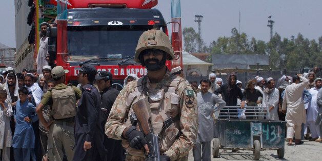 Pakistani troops stand guard while Afghans wait to cross border through the Torkham border crossing in Torkham, Pakistan, Saturday, June 18, 2016. Pakistan reopened the Torkham border crossing with Afghanistan that was closed earlier this week following clashes between the two sides over Pakistan's construction of a gate to curb illegal cross-border movement. (AP Photo/Mohammad Sajjad)