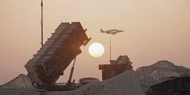 A pair of F-16 fighter jets streak past a Patriot Missile Defense Battery as the sun sets, Monday, Oct. 8, 1990 at an airbase in Saudi Arabia. (AP Photo/John Gaps)