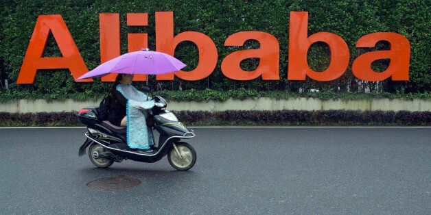 A woman rides a bike past the company logo outside the Alibaba Group headquarters in Hangzhou, in eastern China's Zhejiang province on Friday, May 27, 2016. Alibaba began 17 years ago in the modest living room of a gutsy man with a history of failure. Jack Ma struggled in school, and even Kentucky Fried Chicken refused to hire him. Today, Alibaba is a $15.7 billion e-commerce ecosystem that supports the livelihoods of tens of millions of merchants. Some 423 million shoppers last fiscal year picked through the billion listings that Alibaba's platforms host on any given day. (AP Photo/Ng Han Guan)