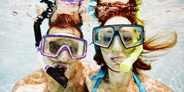 Husband and wife wearing snorkel masks underwater view