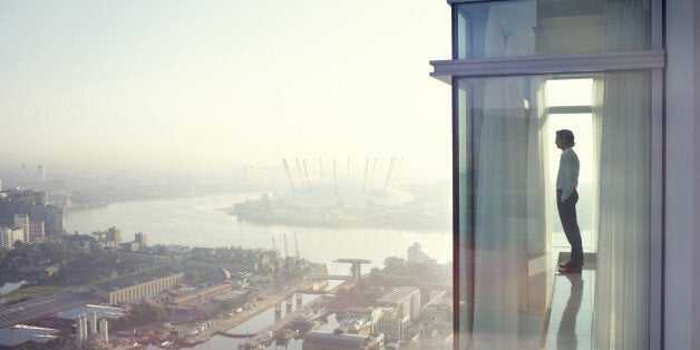 Business executive looking at view from city apartment window early morning