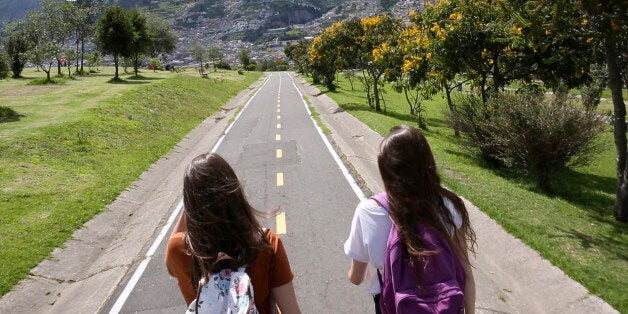 Two students walk down paved trail in park