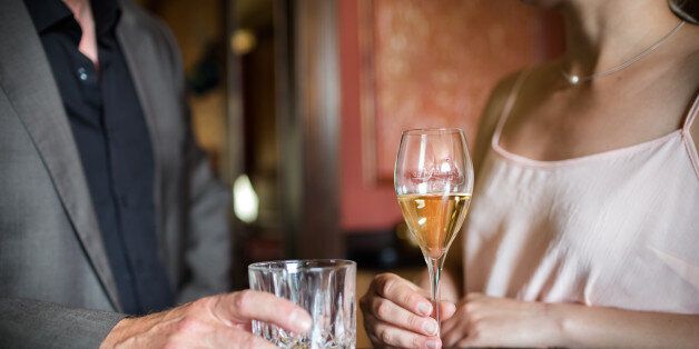 Man and woman flirting at a bar while holding drinks. Close-up shot of their hands.