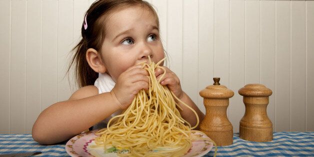Little girl eating spaghetti with her hands