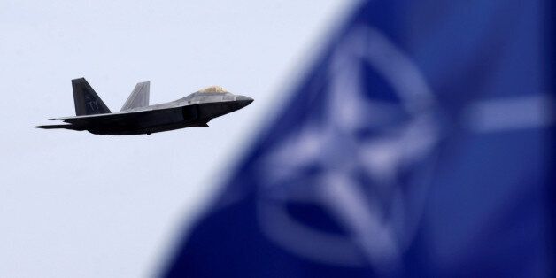 NATO and U.S. flags flutter as U.S. Air Force F-22 Raptor fighter flies over the military air base in Siauliai, Lithuania, April 27, 2016. REUTERS/Ints Kalnins/File Photo