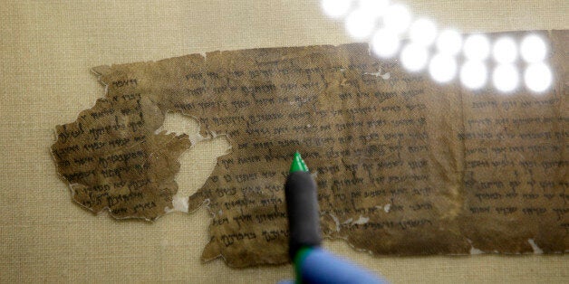 Conservators examine a portion of the Dead Sea Scrolls containing the ten commandments before the scrolls' installation at Discovery Times Square in New York, Thursday, Dec. 15, 2011. (AP Photo/Seth Wenig)