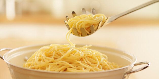 Close up of spoon scooping spaghetti in colander