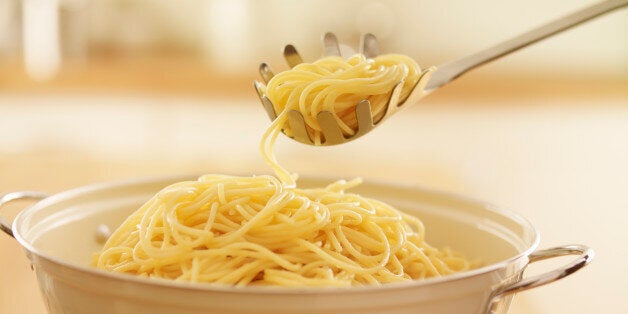 Close up of spoon scooping spaghetti in colander