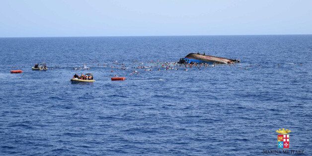 People swim next to an overturned boat off the Libyan coast, Wednesday, May 25, 2016. The Italian navy says it has recovered 7 bodies from an overturned migrant ship off the coast of Libya. Another 500 migrants who on board were rescued safely. A statement from the Italian navy Wednesday says the Bettica patrol ship was responding to a migrant ship in distress when it flipped, sending migrants into the sea. (Marina Militare via AP Photo)