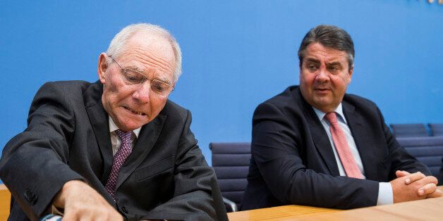 German Finance Minister Wolfgang Schaeuble (R) pours himself a glass of water watched by German Vice Chancellor, Economy and Energy Minister Sigmar Gabriel (R) prior to a press conference in Berlin on April 27, 2016 on a national strategy of promoting electric vehicles by giving purchase subsidies to buyers. / AFP / ODD ANDERSEN (Photo credit should read ODD ANDERSEN/AFP/Getty Images)