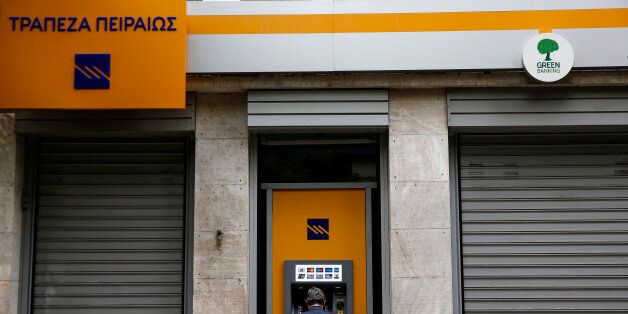 A man makes a transaction at an automated teller machine (ATM) of a Piraeus Bank branch in Athens, Saturday, Oct. 31, 2015. The European Central Bank says Greece's battered banks need 14.4 billion euros ($15.8 billion) in fresh money to get back on their feet and resume normal business. (AP Photo/Yorgos Karahalis)