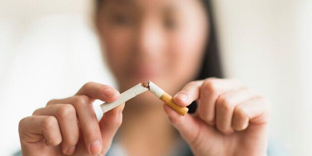 Mixed race teenage girl breaking cigarette in half