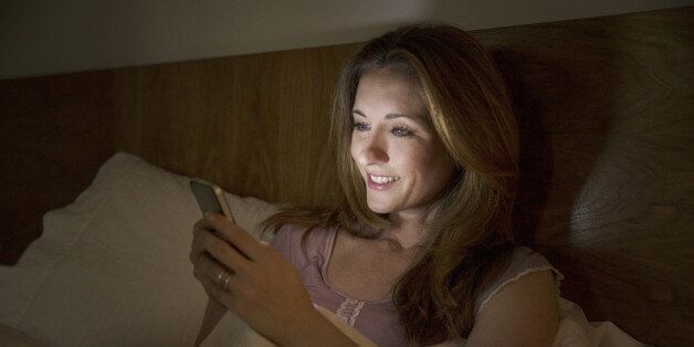 Woman using cell phone in bed