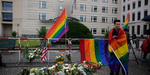 A man stand next to flowers placed in front of the United States embassy during a vigil in Berlin, German, Monday, June 13, 2016 to honor the victims of the attack on the gay nightclub in Orlando, Fla. (AP Photo/Markus Schreiber)