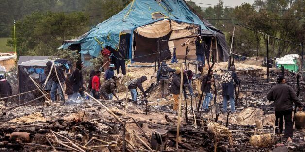 Migrants clean up burnt tents after a massive brawl that left 40 people injured in the 'Jungle' migrant camp in the northern French town of Calais on May 27, 2016.Some 20 people living in the 'Jungle' refugee camp in the northern French port of Calais were injured in a brawl between around 200 Afghans and Sudanese on May 26, 2016. / AFP / PHILIPPE HUGUEN (Photo credit should read PHILIPPE HUGUEN/AFP/Getty Images)