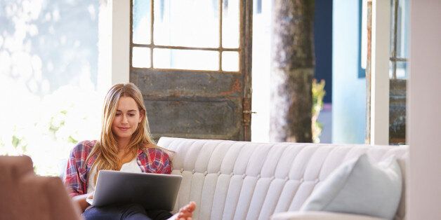 Woman Relaxing On Sofa At Home Using Laptop Computer