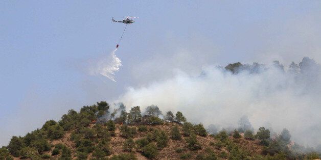 A helicopter drops water on a forest fire in the Cypriot village of Eyrixou in the Troodos mountain area on June 20, 2016.Aircraft from Britain and Greece have joined Cypriot firefighters in the battle to control some of the worst forest fires to have hit the island in years, officials said. Israel had already sent aircraft to Cyprus when a fire broke out on June 18 at Argaka in the northwestern tourist region of Paphos, fanned by strong winds and scorchingly high temperatures. / AFP / SAKIS SAVVIDES (Photo credit should read SAKIS SAVVIDES/AFP/Getty Images)