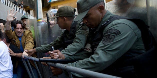 Opposition protesters are removed from the entrance of the headquarters of the National Electoral Council, CNE, by Bolivarian National Guards in Caracas, Venezuela, Thursday, June 9, 2016. Opposition members were turned back from the headquarters of Venezuela's electoral body where the group attempted to enter to demand the government allow it to pursue a recall referendum against President Nicolas Maduro. (AP Photo/Ariana Cubillos)