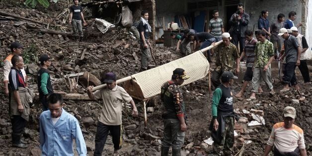 Indonesian villagers and search and rescue team members carry out the body of a landslide victim at Gumelem Kulon village in Banjarnegara on June 19, 2016. Flash flooding and landslides in Indonesia have killed 24 and left more than two dozen missing, an official said on June 19, with mud avalanches burying people inside their homes. / AFP / ROHMAT SYARIF (Photo credit should read ROHMAT SYARIF/AFP/Getty Images)