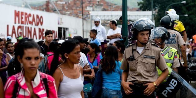 Police keep guard as people line up to buy groceries in a supermarket at Catia neighborhood in Caracas, on June 11, 2016. Facing mounting pressure from food shortages, looting and increasingly violent protests, Venezuelan authorities on Friday announced the next stage of a recall referendum against embattled President Nicolas Maduro. / AFP / FEDERICO PARRA (Photo credit should read FEDERICO PARRA/AFP/Getty Images)