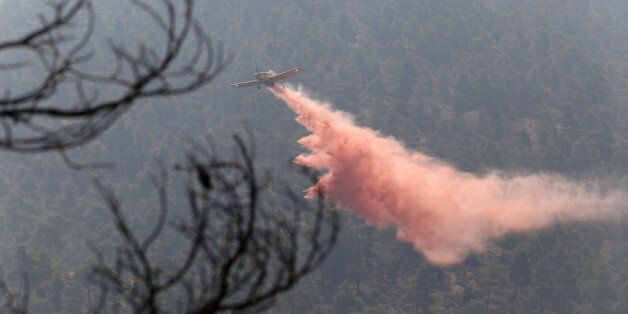 A firefighting aircraft drops fire retardant material in efforts to contain a huge forest fire that continues to rage out of control for a third day in the mountainous areas southwest of Cyprus' capital Nicosia Tuesday, June 21, 2016. The fire has claimed the lives of two fire fighters. More planes from Italy and France are expected later Tuesday to join 16 other aircraft from Greece, Israel, Cyprus and British forces stationed on two military bases on the east Mediterranean island in battling the fire. (AP Photo/Philippos Christou )