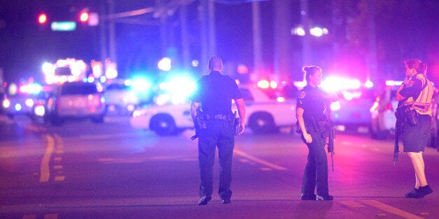 Police officers stand guard down the street from the scene of a shooting involving multiple fatalities at a nightclub in Orlando, Fla., Sunday, June 12, 2016. (AP Photo/Phelan M. Ebenhack)