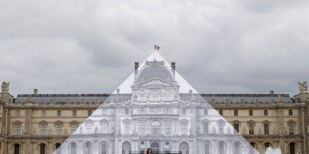 Tourists walk around theJR project at the Louvre Pyramid in Paris, Tuesday, May 24, 2016. For his latest bold project, street artist JR is creating an eye-tricking installation at the Louvre Museum that makes it seem as if the huge glass pyramid at the heart of the courtyard has disappeared. (AP Photo/Francois Mori)