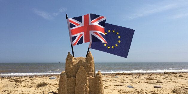 A sandcastle on a British beach with UK and European Union flags