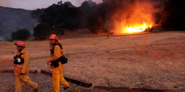 Los Angeles County firefighters approach a brush fire in the foothills outside of Calabasas, Calif. on Saturday, June 4, 2016. A fast-moving brush fire sweeping through hills northwest of downtown Los Angeles has damaged homes and prompted neighborhood evacuations. (AP Photo/Richard Vogel)