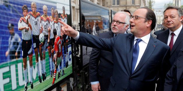 French President Francois Hollande (2ndL), flanked with French Soccer specialist Pierre Louis Basse (L), comment on a photo of Bulgarian soccer player Hristo Stoitchkov shooting a free kick against Germany in 1994 Euro quarter final during a visit of an exhibition entitled