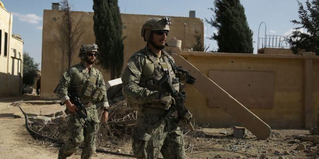 Armed men in uniform identified by Syrian Democratic forces as US special operations forces walk in the village of Fatisah in the northern Syrian province of Raqa on May 25, 2016. US-backed Syrian fighters and Iraqi forces pressed twin assaults against the Islamic State group, in two of the most important ground offensives yet against the jihadists. The Syrian Democratic Forces (SDF), formed in October 2015, announced on May 24 its push for IS territory north of Raqa city, which is around 90 kilometres (55 miles) south of the Syrian-Turkish border and home to an estimated 300,000 people. The SDF is dominated by the Kurdish People's Protection Units (YPG) -- largely considered the most effective independent anti-IS force on the ground in Syria -- but it also includes Arab Muslim and Christian fighters. / AFP / DELIL SOULEIMAN (Photo credit should read DELIL SOULEIMAN/AFP/Getty Images)