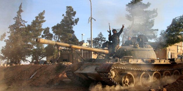 In this photo taken on Wednesday, Feb. 17, 2016, a volunteer fighter with the Syrian Government forces sits atop a tank in the province of Raqqa, Syria. In recent weeks, Syrian government forces captured dozens of villages and towns across the country. (Alexander Kots/Komsomolskaya Pravda via AP)