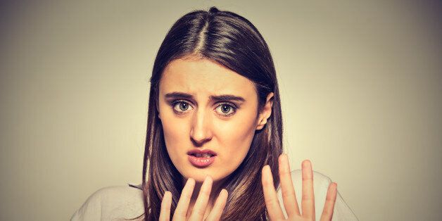 Closeup portrait of scared woman raising hands up in defense afraid about to be attacked or avoiding unpleasant situation, isolated on gray background. Negative human emotion facial expression feeling