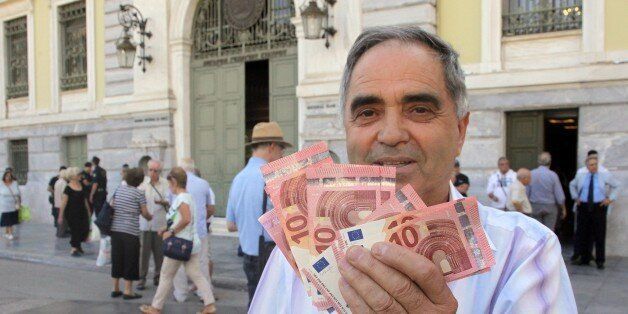 Pensioner Giorgos Petropoulos shows ten euros notes who receive from National Bank of Greece in Athens, Wednesday, July 1, 2015. Pensioners are the forgotten victims of the Greek crisis. Their monthly payments have been cut in recent years, and since many lack bank cards they were totally cut off from their funds until Wednesdayâs special bank sessions allowed them partial access. (AP Photo/Spyros Tsakiris)