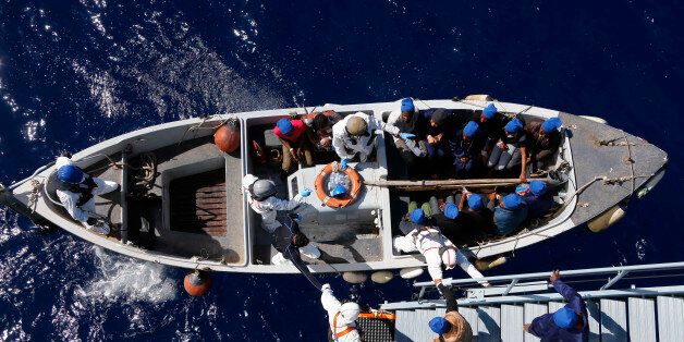 In this March 29, 2016 picture migrants get help by Italian sailors to transfer from the German combat supply ship 'Frankfurt am Main' to the their ship 'Grecale' after being rescued during EUNAVFOR MED Operation Sophia in the Mediterranean Sea off the coast of Libya. (AP Photo/Matthias Schrader)