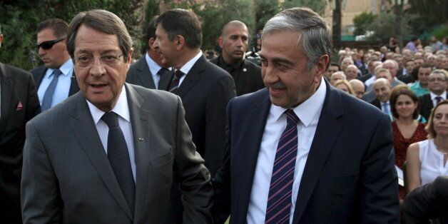 Turkish Cypriot leader Mustafa Akinci (R) and Greek Cypriot leader, Cypriot President Nicos Anastasiades, hold hands during a bicommunal event organized by the Cyprus Chamber of Commerce and Industry and the Turkish Cypriot Chamber of Commerce in Nicosia July 8, 2015. REUTERS/Yiannis Kourtoglou