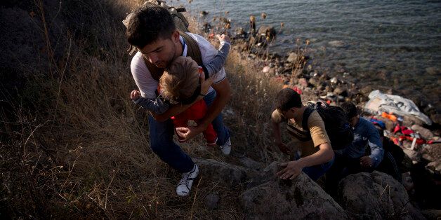 FILE - In this Wednesday, Sept. 9, 2015 file photo, Afghan refugees climb up to a field after arriving from Turkey to Lesbos island, Greece, on a dinghy. They have to walk around 55 kilometers (34 miles) to reach the capital of Lesvos, Mytillini. (AP Photo/Petros Giannakouris, File)