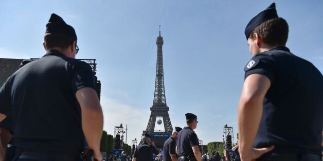 Policemen stand as they watch people gathering in the fan zone behind the Eiffel Tower, on the Champs de Mars during the opening of the Paris fan zone one day before the start of the Euro 2016 football championship, on June 9, 2016. AFP PHOTO / ALAIN JOCARD / AFP / ALAIN JOCARD (Photo credit should read ALAIN JOCARD/AFP/Getty Images)