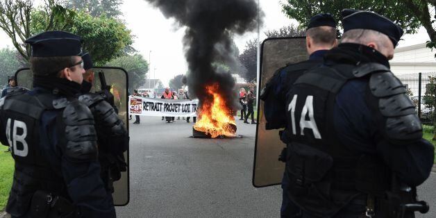French riot police stand in front of French CGT union's members next to tires on fire during a protest against the government's planned labour law reforms at the Simmons factory in Saint Amand les Eaux, northern France on May 31, 2016 during a visit of the French Economy Minister. / AFP / FRANCOIS LO PRESTI (Photo credit should read FRANCOIS LO PRESTI/AFP/Getty Images)