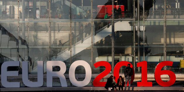 People stand in front of a sign announcing the UEFA Euro 2016 tournament near the Lille Europe railway station in Lille, France, March 12 , 2016. France will host the Euro 2016 soccer tournament from June 10 to July 10. REUTERS/Pascal Rossignol