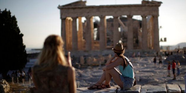 Tourists observe the Parthenon temple ruins on Acropolis Hill at sunset in Athens, Greece, on Monday, July 20, 2015. German Chancellor Angela Merkel held out the prospect of limited debt relief as crisis-ravaged Greece prepares to reopen its banks three weeks after they were shut. Photographer: Matthew Lloyd/Bloomberg via Getty Images