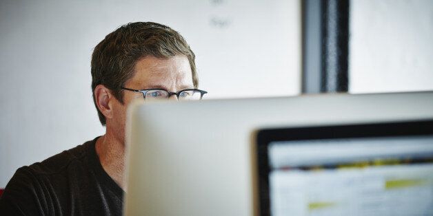 Businessman sitting at desk in high tech startup office working on computer