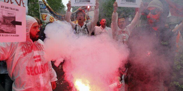 Railway workers protestors burn flares during a demonstration held as part of nationwide labor actions in Paris, France, Thursday, May 26, 2016. French protesters scuffled with police, dock workers set off smoke bombs and union activists disrupted fuel supplies and nuclear plants Thursday in the biggest challenge yet to President Francois Hollande's government as it tries to give employers more flexibility. (AP Photo/Francois Mori)