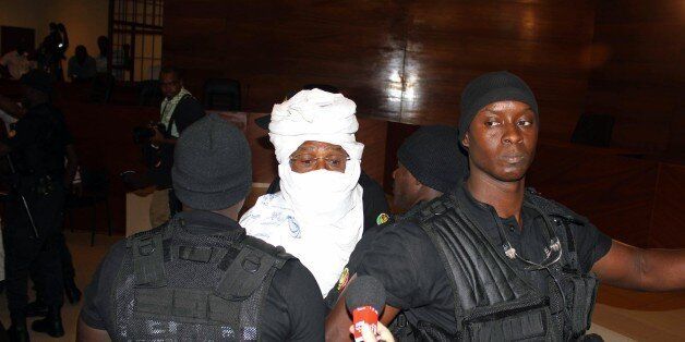 CORRECTS NAME OF PHOTOGRAPHER Security personnel surround former Chadian dictator Hissene Habre inside the court in Dakar, Senegal, Monday, July 20, 2015. The trial of former Chadian dictator Hissene Habre, accused of overseeing the deaths of thousands, had a chaotic beginning Monday as security forces ushered the ex-leader into and then out of the Senegal courtroom amid protests by his supporters.(AP Photo/Ibrahima Ndiaye)
