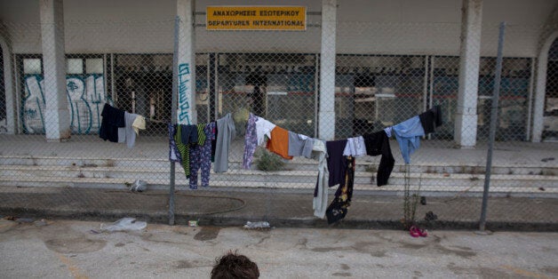 A boy stands in front of a terminal of the old international airport which is used as a temporary camp in Athens, on Saturday, April 23, 2016. Greece's Prime Minister Alexis Tsipras is criticizing Turkey for preventing a NATO force in the Aegean Sea from expanding its activities further south as part of its deployment to help tackle the refugee crisis. (AP Photo/Yorgos Karahalis)