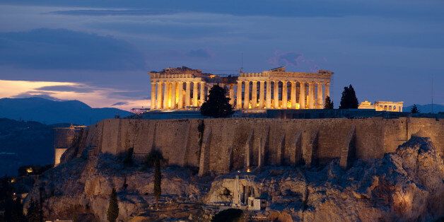 View onto the illuminated Parthenon temple on the Akropolis of Athens at dusk. The Dionysos theatre is seen at the lower left.