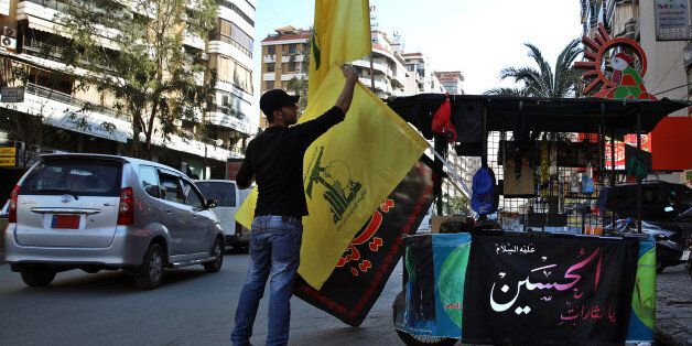 In this Feb. 29, 2016 photo, a vendor sells Hezbollah and religious flags and other memorabilia , in the southern suburbs of Beirut, Lebanon. Lebanon's central bank governor said Monday, April 18, 2016 that Beirut will abide by a U.S. law that imposes sanctions on banks that knowingly do business with the militant Hezbollah group. (AP Photo/Bilal Hussein)